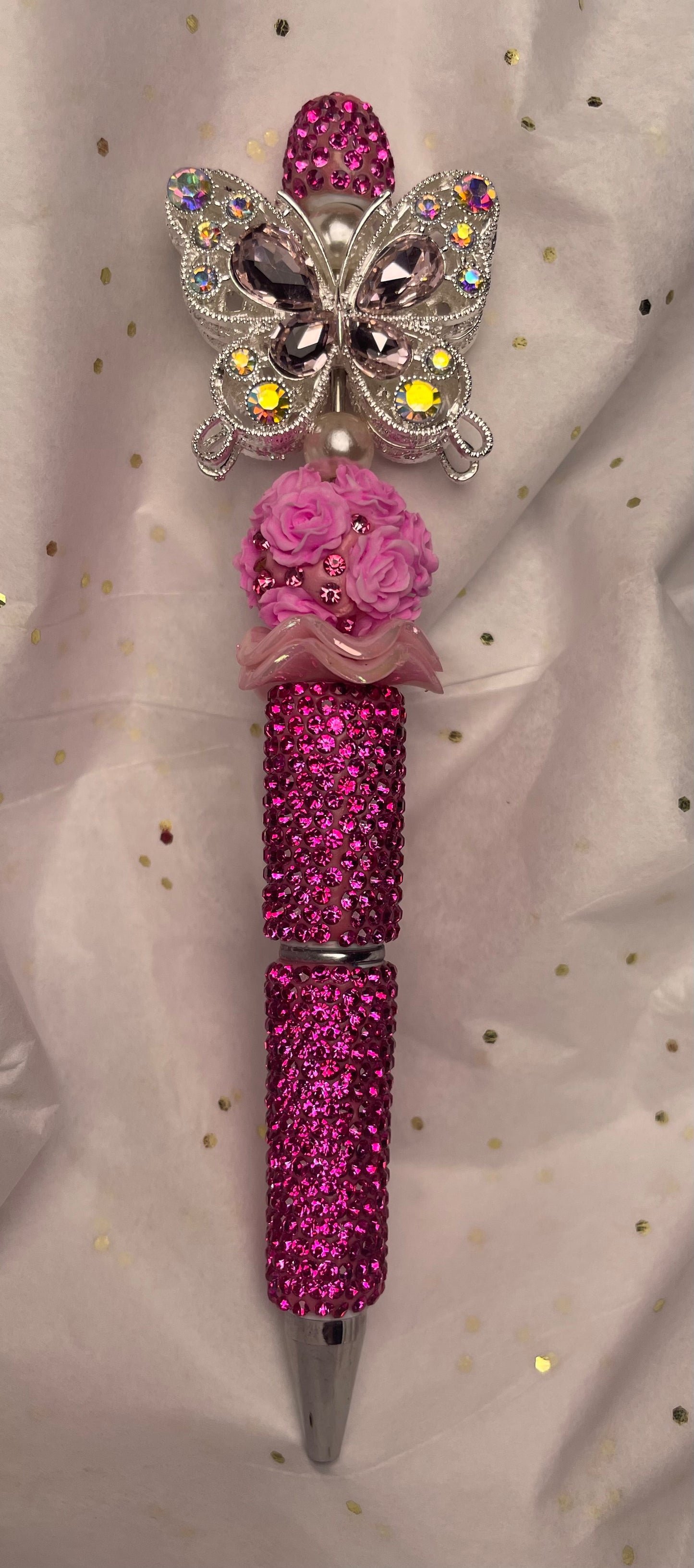 Pink glittery pen with butterfly and rose design on a light background